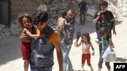 Сирійські чоловіки несуть дітей серед уламків зруйнованих будівель після повітряних ударів по Алеппо, 25 липня 2016 року