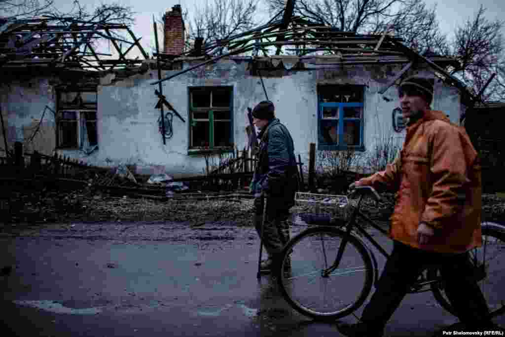 Місцеві жителі проходять повз зруйнований будинок Раїси Казакової у Дебальцеві