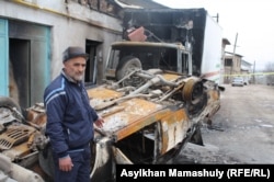Житель села Ынтымак Сарыагашского района Южно-Казахстанской области Адильжан Хасанов стоит у своего поврежденного поджогом дома и у своей сожженной машины. 10 февраля 2015 года.