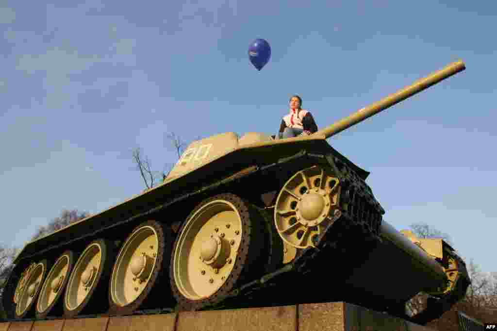 Germany -- A girl holds an EU balloon on a World War II era Soviet tank at the Soviet War memorial near Berlin's Brandenburg Gate, March 24, 2007