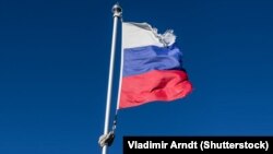 Russia – Tattered russian flag over blue sky.