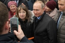 Russian President Vladimir Putin poses for pictures with a member of the public. (file photo)