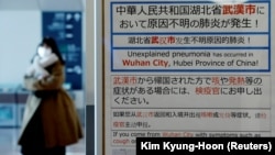 O femeie care a sosis Japonia trece pe lângă anunțul privind carantina instituită pentru călătorii care vin din Wuhan, centrul noii epidemii