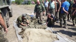 Український військовий «підписує» тіла побратимів, загиблих унаслідок танкової атаки російських гібридних сил. Донбас, 4 липня 2014 року
