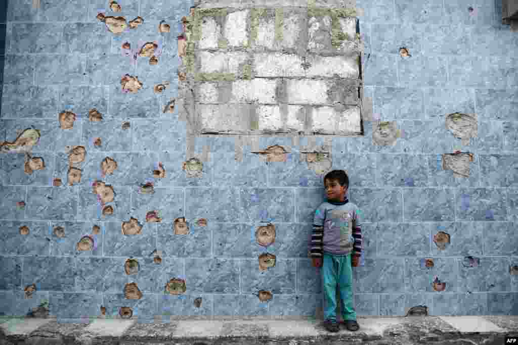 A Syrian boy stands against a bullet-riddled wall in the rebel-held town of Douma, on the eastern outskirts of the Syrian capital, Damascus. (AFP/Abd Doumany)