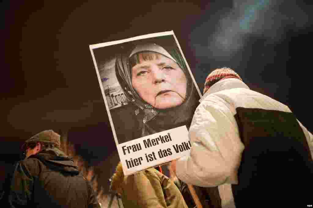 A participant in a rally with the anti-Islamic Pegida movement holds up a picture of Chancellor Angela Merkel wearing a head scarf. Islam is part of German life, Merkel said on January 12, even as a group of anti-Islam and anti-refugee protesters geared up for controversial marches that have become a weekly fixture in the eastern city. (epa/Arno Burgi)