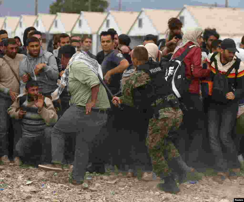 A police officer hits a man with a baton as he tries to maintain order while migrants wait for trains at a temporary camp near Gevgelija, Macedonia. Macedonia has organized trains twice a day to the north border where migrants cross into Serbia to make their way to Hungary. Since June, Macedonian authorities have said that more than 60,000 migrants have entered the country. (Reuters/Stoyan Nenov) 