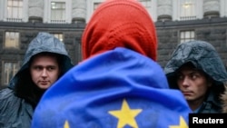 Ukraine -- A protester wrapped in a EU flag attends a rally to support EU integration as police stand guard in front of the cabinet of ministers building in Kyiv, November 25, 2013