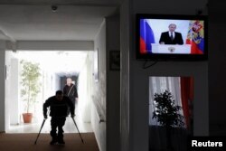 Residents of a retirement home walk along a corridor during a TV broadcast showing President Vladimir Putin delivering his annual state-of-the-nation speech on December 4.