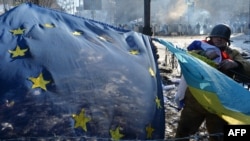 An antigovernment opposition activist places European Union and Ukrainian flags side by side at a barricade in the Ukrainian capital of Kyiv on February 2 as tens of thousands of protesters rallied to demand President Viktor Yanukovych resign.