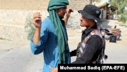 Співробіник сил безпеки Афганістану здійснює обшук перехожого в провінції Кандагар