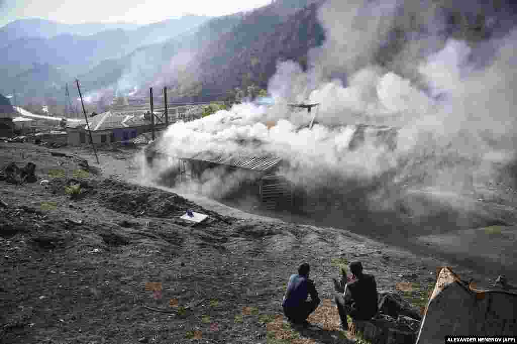 Residents watch houses smolder in Charektar village, known in Azeri as Caraktar, in the district of Karvachar (Kalbacar in Azeri). The mountainous district in Azerbaijan to the west of Nagorno-Karabakh is being vacated by Armenians and returned to Baku&rsquo;s control under a Russian-brokered truce.