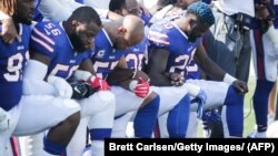 Играчите на Бафало Билс клечат за време на интонирањето на американската химна пред натпреварот против Денвер Бронкос на 24 септември во Њујорк
