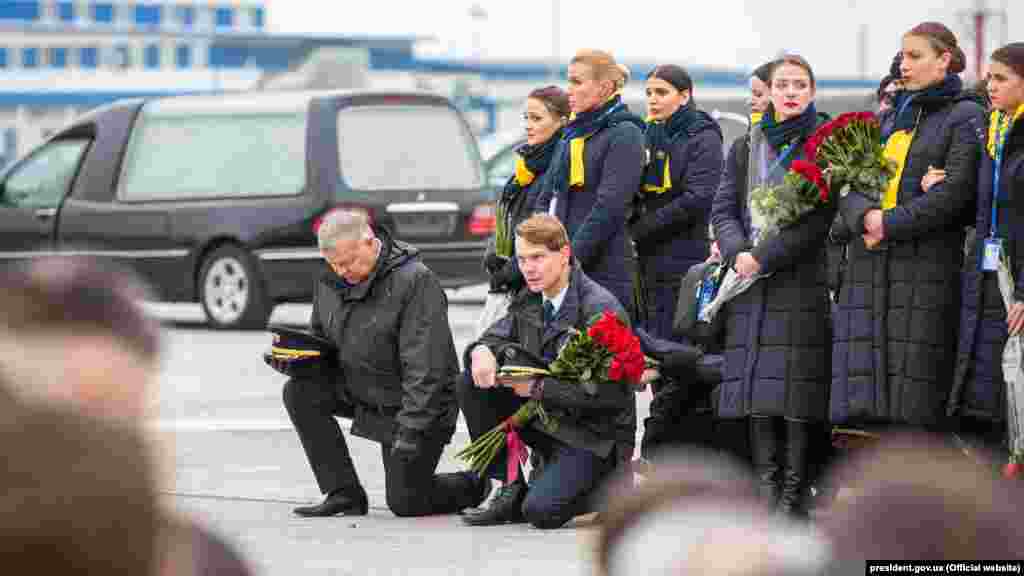 Airline employees kneel to pay respect to their colleagues who died in the plane crash.