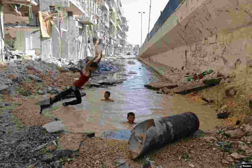 A boy dives into a crater filled with water in the al-Shaar district of Aleppo, Syria, on July 10. Activists said the pit was the result of bombing by government forces. (Hosam Katan, Reuters)