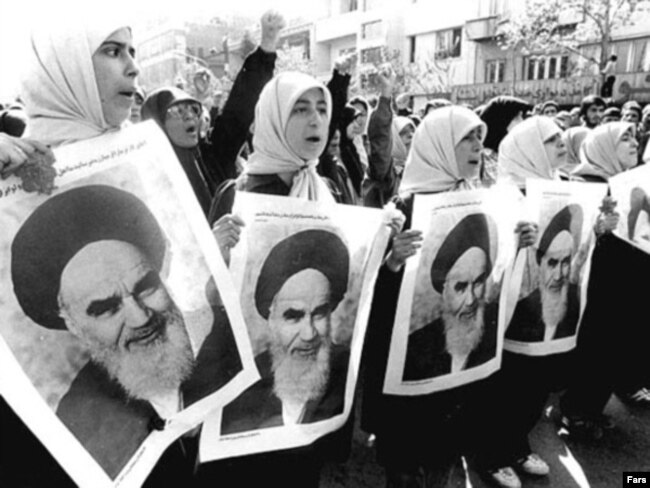 Iran – Girls supporters hold portraits of the religious leader of the revolution, Ayatollah Ruhollah Khomeini. 1979.