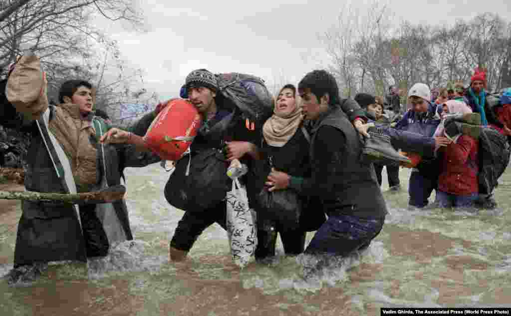 A woman is supported by two men while crossing a river, as these refugees attempt to reach Macedonia using a route that would bypass a border fence, on March 14, 2016. Contemporary Issues -- Second Prize, Singles (Vadim Ghirda, AP)