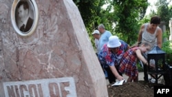 People light candles at the presumed grave of the late Romanian dictator Nicolae Ceausescu at Ghencea cemetery in Bucharest on July 21, after the exhumations.