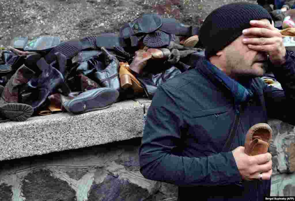 A man reacts as he holds a child's shoes while HIV-infected Ukrainians carry hundreds of pairs of shoes of people who died from AIDS to the cabinet of ministers during their rally called "Stop genocide!" in Kyiv. (AFP/Sergei Supinsky)