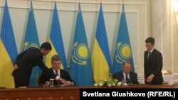 Президент Казахстана Нурсултан Назарбаев (сидит справа) и президент Украины Петр Порошенко подписывают документы после переговоров. Астана, 9 октября 2015 года.