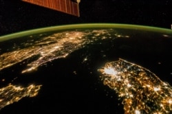 The Korean Peninsula photographed from space, showing the darkness of North Korea in the center of the image, and South Korea at the bottom right.