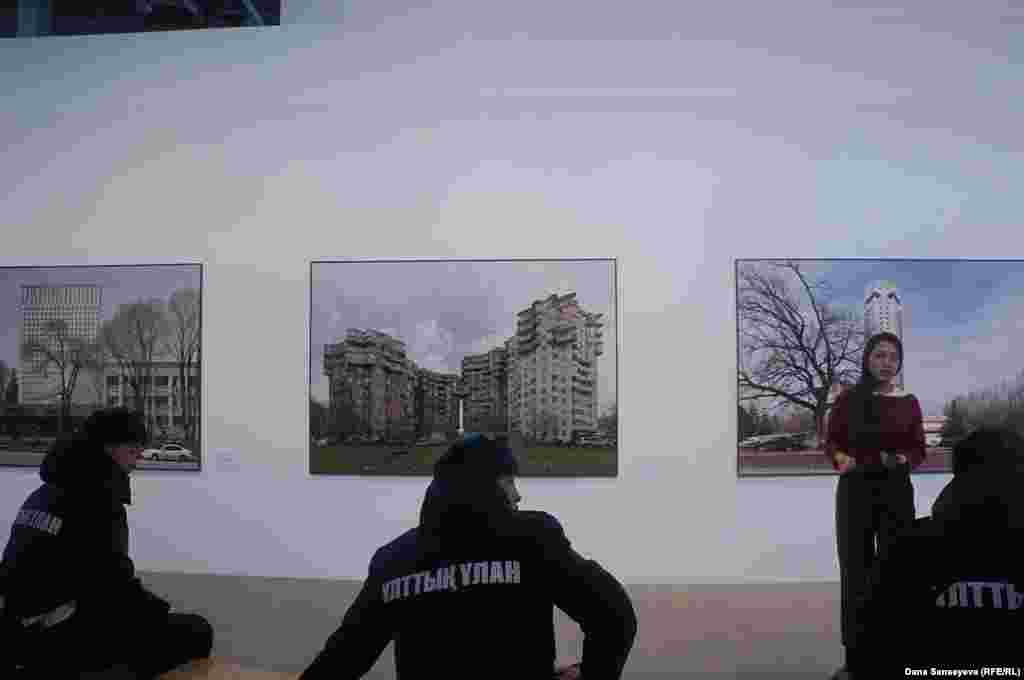 Служащие Национальной гвардии Казахстана слушали, как гид рассказывала о советской модернистской архитектуре Алматы, запечатленной российским архитектурным фотографом Юрием Пальминым.