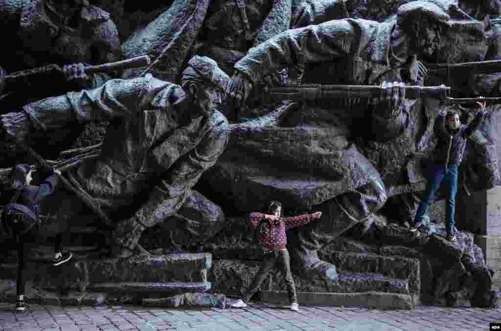 Children play next to the bronze monument at the World War II museum complex in Kyiv, Ukraine. Ukrainians marked the 71st anniversary of the liberation of Ukraine from Nazi occupation during World War II. (epa/Roman Pilipey)