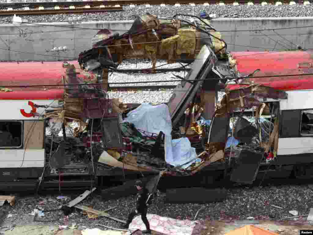 A Spanish policeman walks past a hole blasted through a train in an explosion at Madrid's Atocha train station after an explosion March 11, 2004. Simultaneous explosions killed at least 173 people on packed rush-hour trains in Madrid on Thursday in pre-election attacks that could be the worst ever by Basque separatist group ETA, officials said. REUTERS/Andrea Comas 