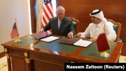 رکس تیلرسون (چپ) وزیر خارجه آمریکا در حال امضای سند تشدید مبارزه با تروریسم با محمد بن عبدالرحمن آل ثانی، همتای قطری‌اش.