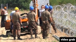 Угорські військові будівельники зводять металевий паркан поруч із загорожею з колючого дроту на кордоні з Сербією