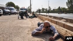 People and soldiers lying on the ground for cover at the scene of an attack on a military parade in the southwestern Iranian city of Ahvaz.