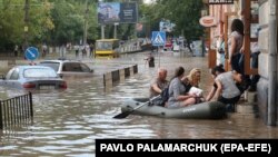 Чоловік на гумовому човні допомагає людям пересуватися затопленою частиною у місті Львові після сильної зливи, 17 серпня 2018 року