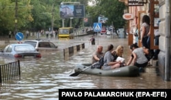 Чоловік на гумовому човні допомагає людям пересуватися затопленою частиною у місті Львові після сильної зливи, 17 серпня 2018 року