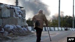 Пожилая женщина проходит мимо КПП по дороге, ведущей в аэропорт Донецка. 2 октября 2014 года.
