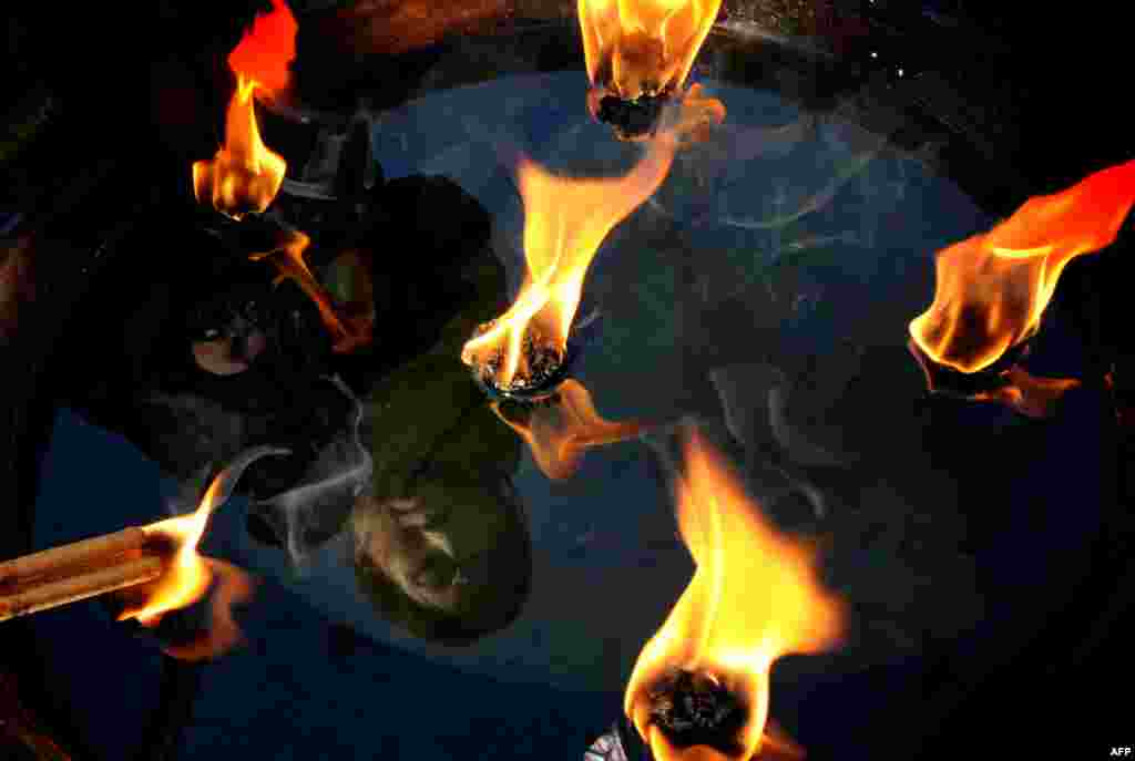 A woman lights joss sticks to pray for prosperity and well-being on the first day of the Year of the Dragon at the Dongyue Temple in Beijing.