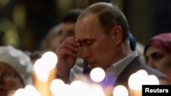 Russian President Vladimir Putin crosses himself as he attends an Orthodox Christmas service at the Holy Face of Christ the Savior Church in the southern Russian city of Sochi early on January 7.