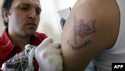 A Turkish tattoo artist gets to work on the arm of a young Turk who has already a Turkish flag tattooed on his bicep -- something Turkey's top Islamic body says he should remove.