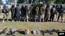 Alleged Taliban militants stand handcuffed near seized weapons in Nangarhar province (file photo).