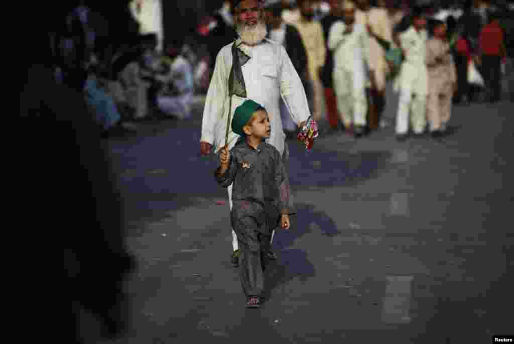 A boy wearing a religious turban carries a flag as he walks along a road during a procession marking Eid-e Milad-ul-Nabi, the birthday celebrations of Prophet Muhammad in Karachi, Pakistan. (Reuters/Akhtar Soomro)