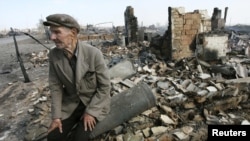 A man sits amid the ruins of his home after the spread of a forest fire from Kazakhstan to the village of Nikolaevka.