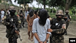 Members of the Afghan National Directorate of Security (NDS) escort four suspected Taliban members allegedly involved in criminal activities in Jalalabad. (file photo)