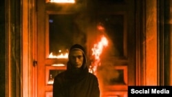 Петр Павленский на фоне горящей двери здания ФСБ.