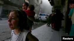 دو دختر سوری و کودکی هشت ماهه از نزدیک یک کاروان هلال احمر که در حاشیه دمشق هدف موشک قرار گرفته می‌گریزند
