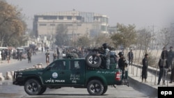 Armed security officials stand guard near the scene where at least four people were reportedly killed and 11 others were injured in a suicide attack targeting a vehicle carrying security personnel, in downtown Kabul on November 16.