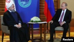 Iranian President Hassan Rohani (left) meets with Russian President Vladimir Putin on the sidelines of the SCO summit in Qingdao, China, on June 9.