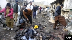 Local residents look at clothes left in a pile at the site of overnight twin suicide bombings in Quetta on January 10.