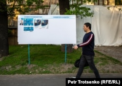 Қазақстан президенттігіне кандидаттардың сайлау жарнамалары ілінген жерден өтіп бара жатқан адам. Алматы, 13 мамыр 2019 жыл.