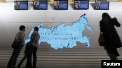 People stand near screens displaying preliminary results of the presidential elections at Vladimir Putin's campaign headquarters in Moscow on March 4.