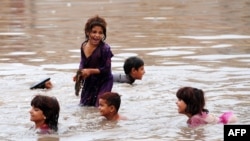 Pakistani children play in floodwaters following heavy rain in Aza Kheil, some 40 kilometers from Peshawar.