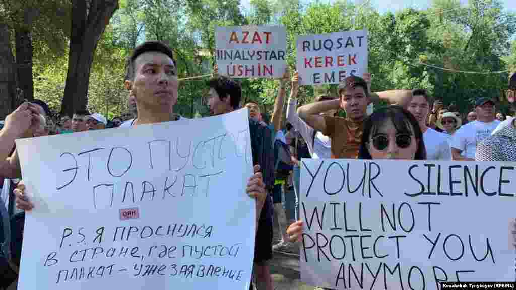 Плакат слева, похоже, является отсылкой к случаю в Уральске, где&nbsp;молодого активиста Аслана Сагутдинова, который вышел на площадь с чистым листом бумаги, задержали полицейские.